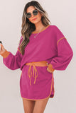Woman wearing a magenta dress with a belt against a white background