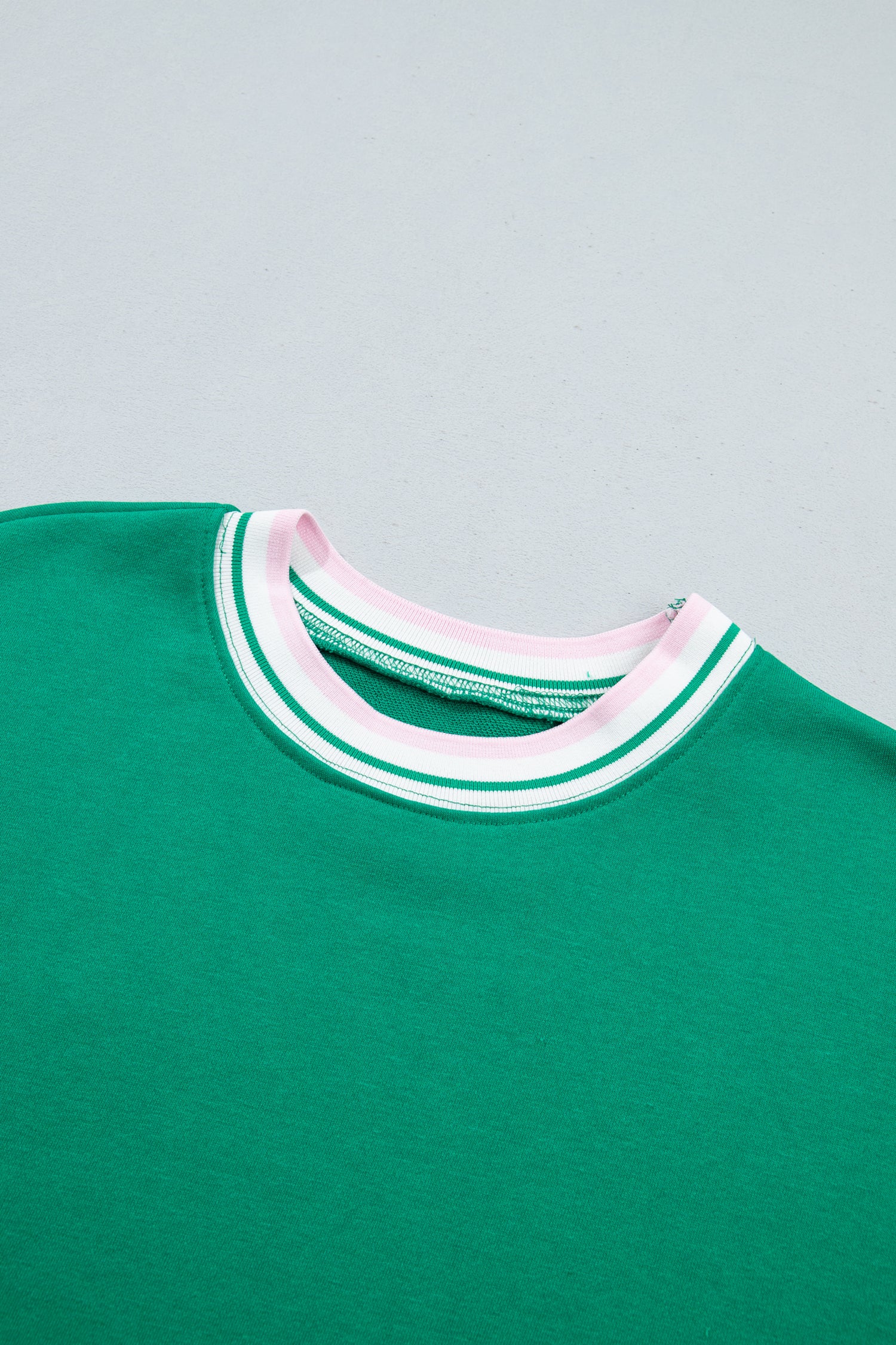 Close-up of a green crewneck sweatshirt featuring a white and green 