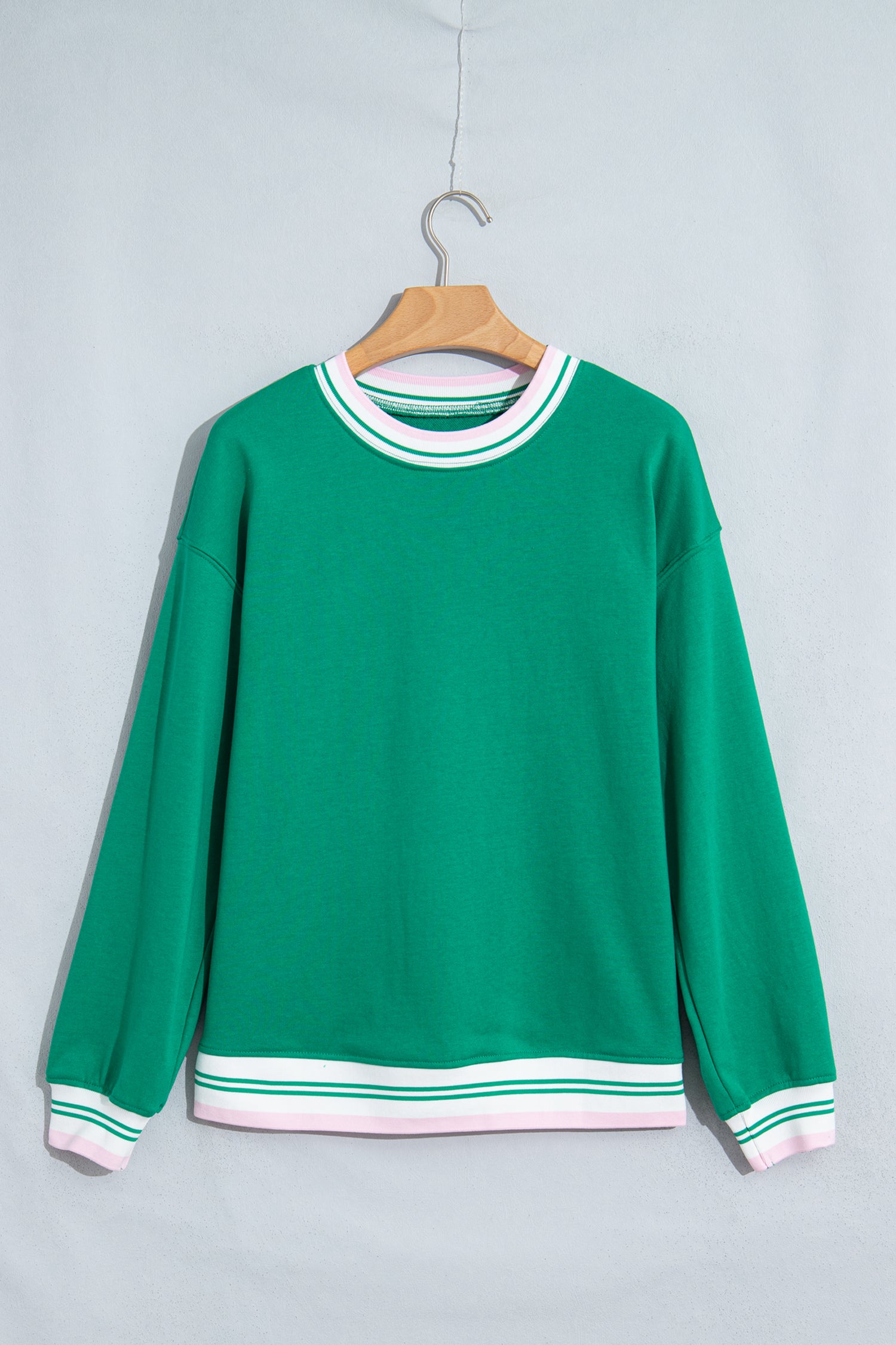 A green crewneck sweatshirt with white and green striped ribbed trim