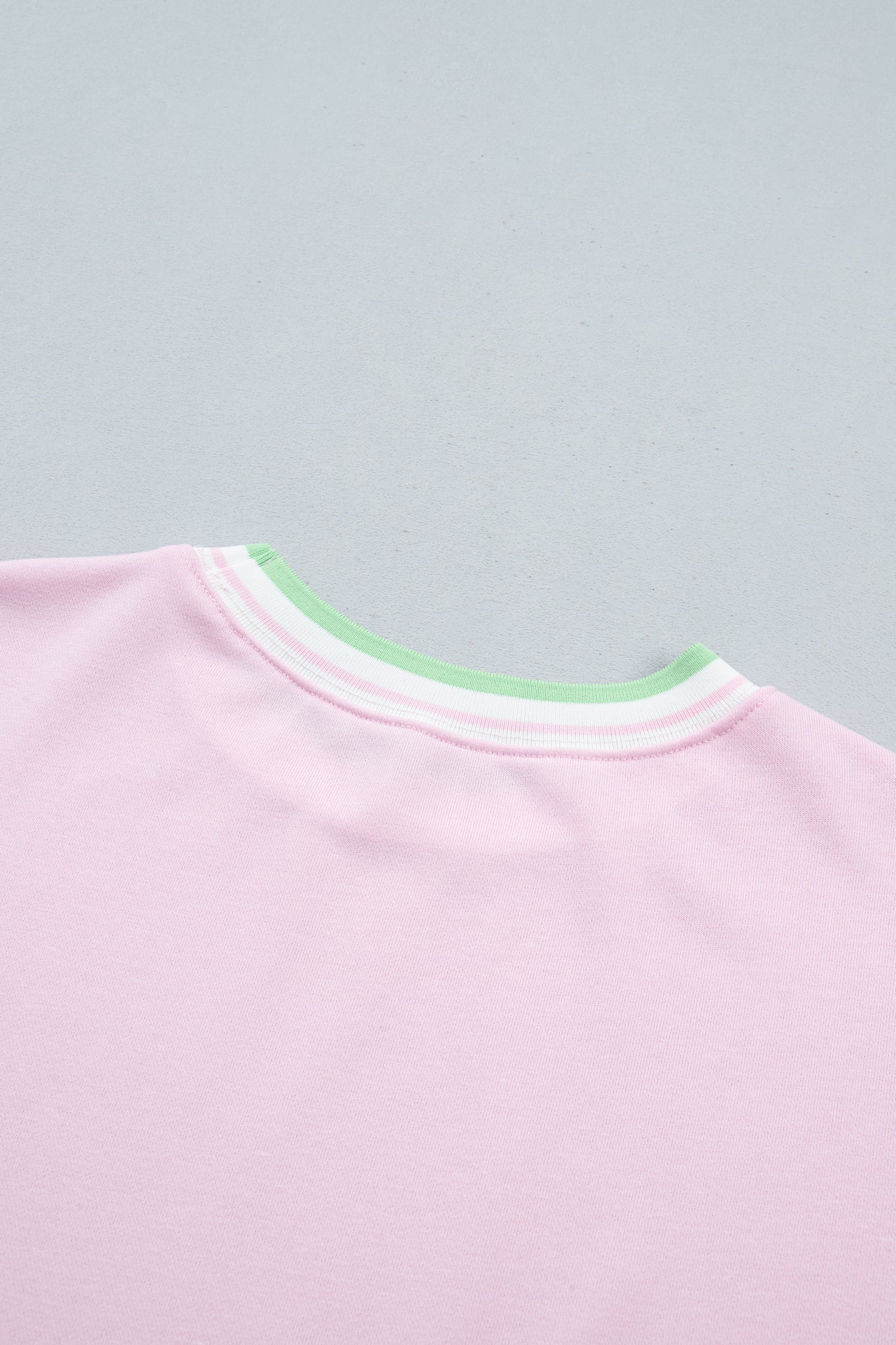 Close-up of a light pink crewneck sweatshirt showing the ribbed collar 
