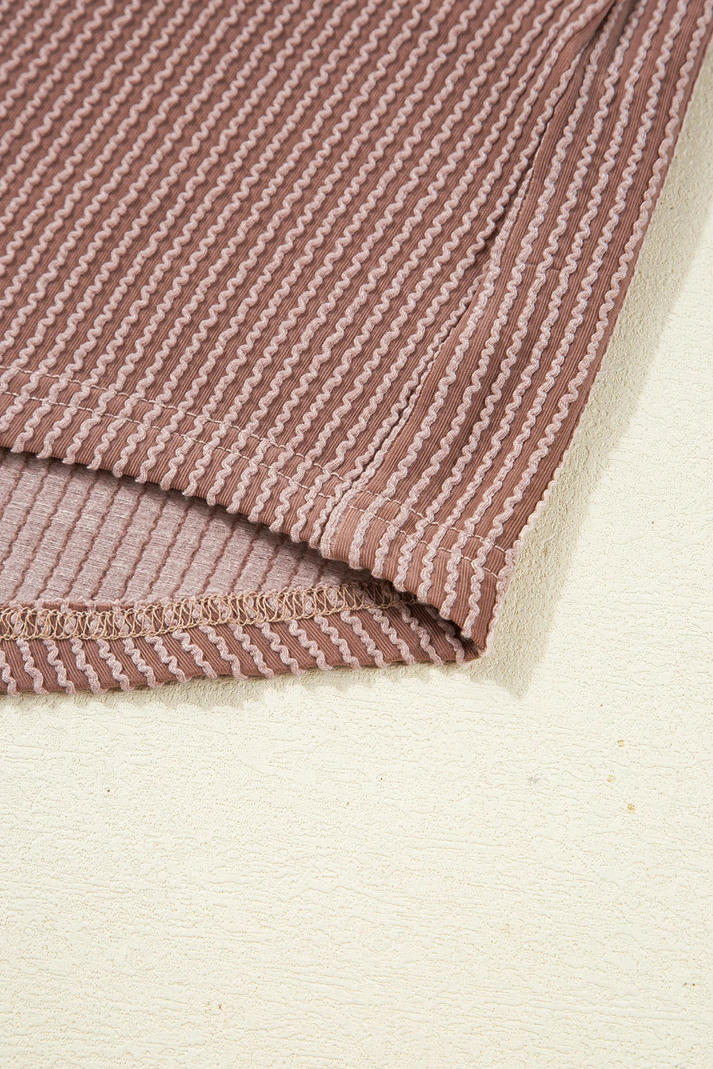 Close-up of a folded fabric with a subtle pattern on a beige background.