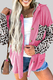 Woman wearing a pink and leopard print jacket with denim shorts on a plain background.