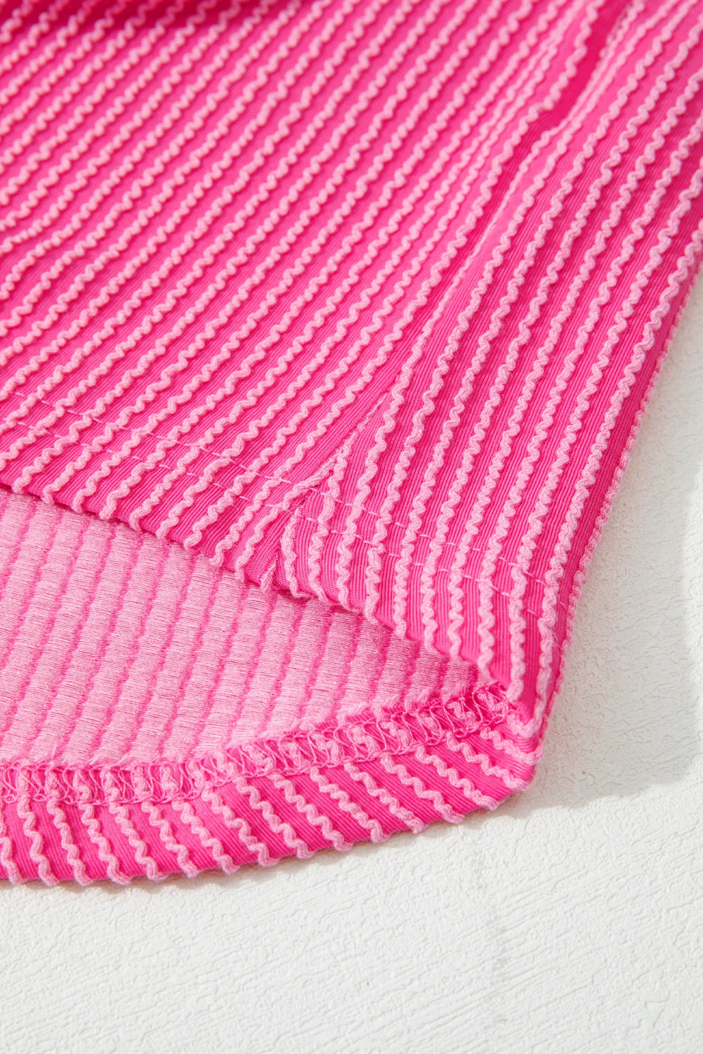 Close-up of a pink textured fabric on a white background.