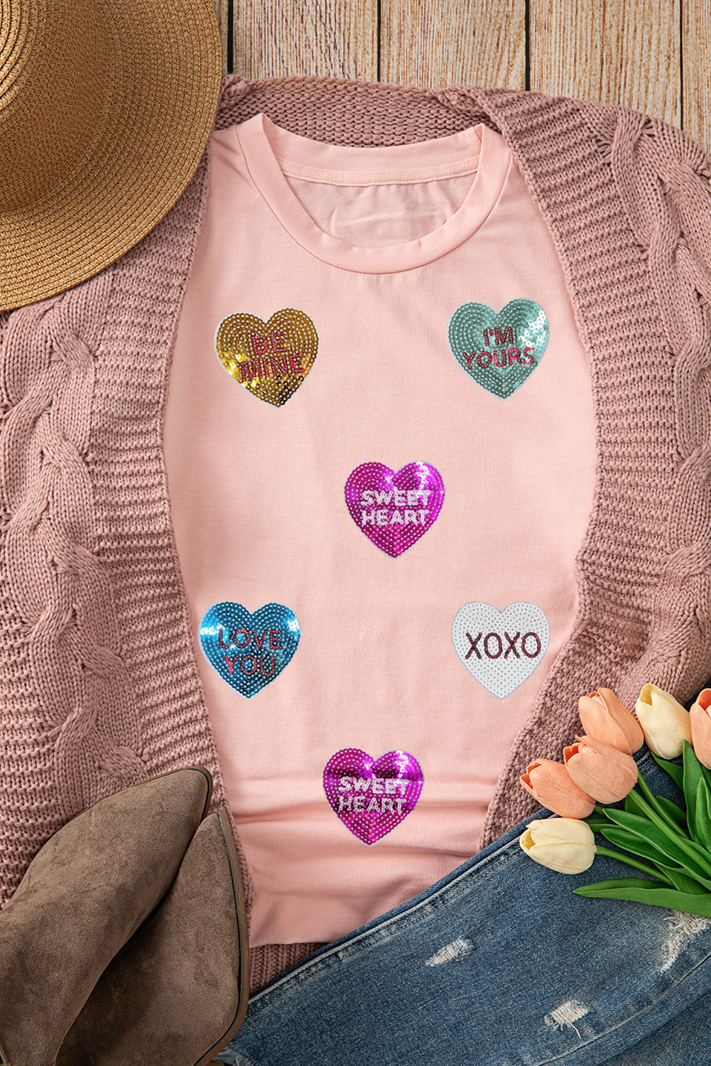 Pink t-shirt with heart-shaped designs on a wooden surface
