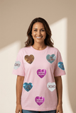 Woman wearing a pink t-shirt with heart-shaped designs and text on a beige background