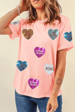 Person wearing a pink t-shirt with colorful heart-shaped sequin designs on a beige background