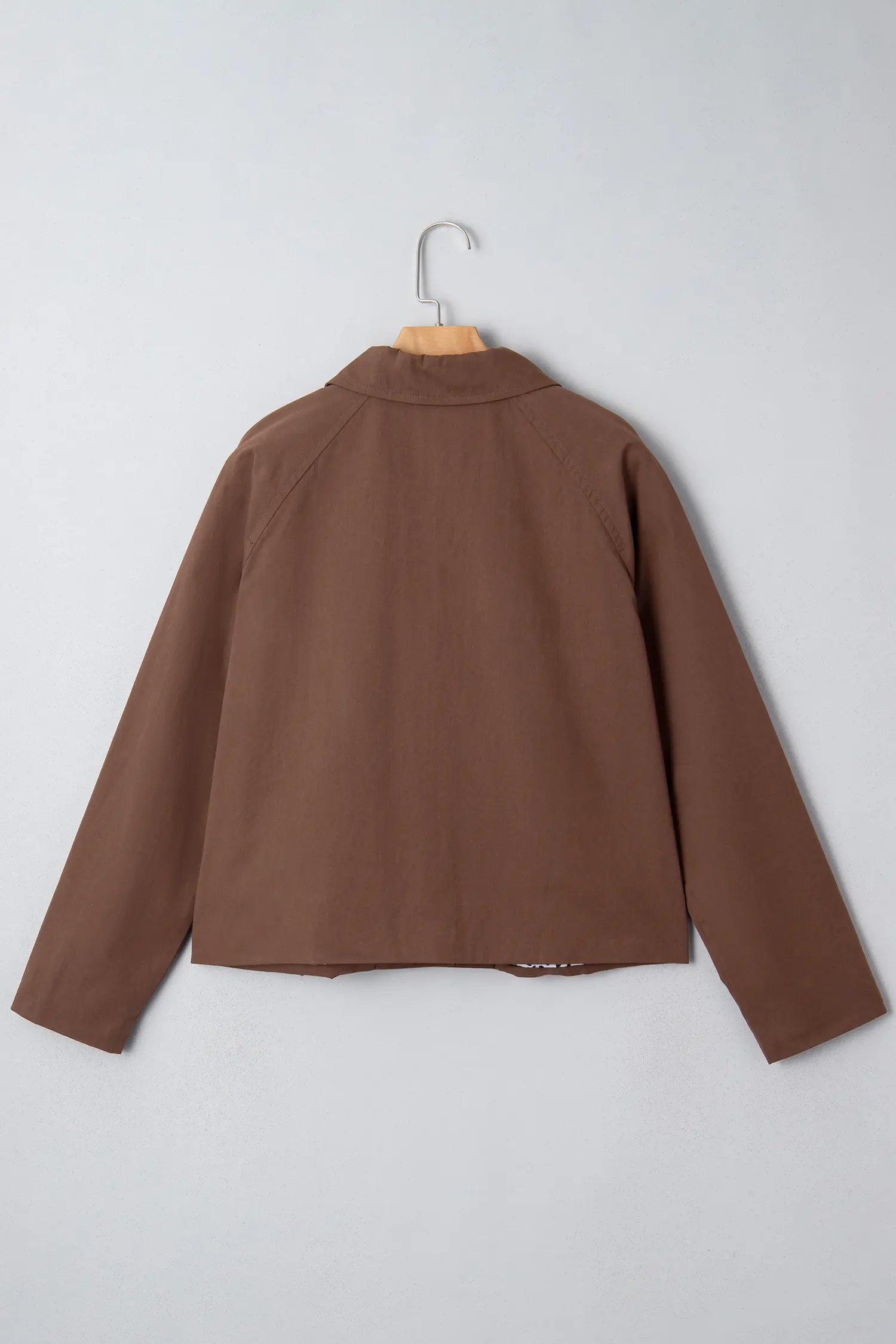 Brown jacket on a hanger against a light gray background
