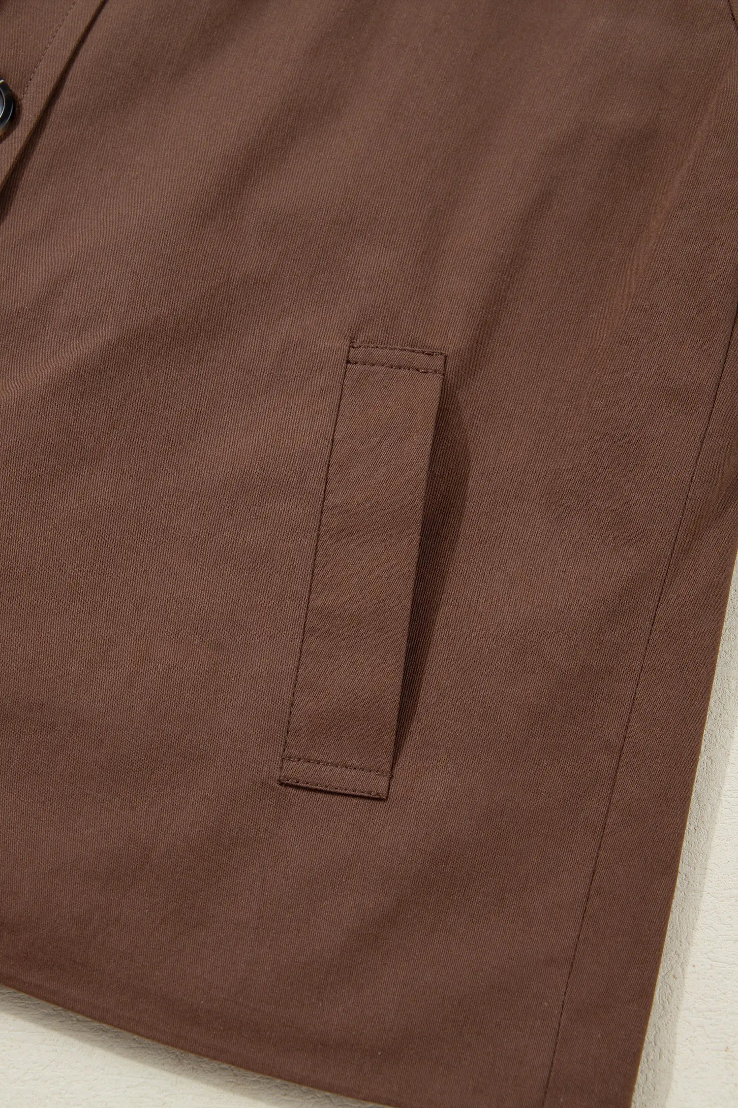 Close-up of a brown jacket with a pocket on a light background