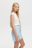 Woman wearing a white sleeveless top and light blue shorts on a white background
