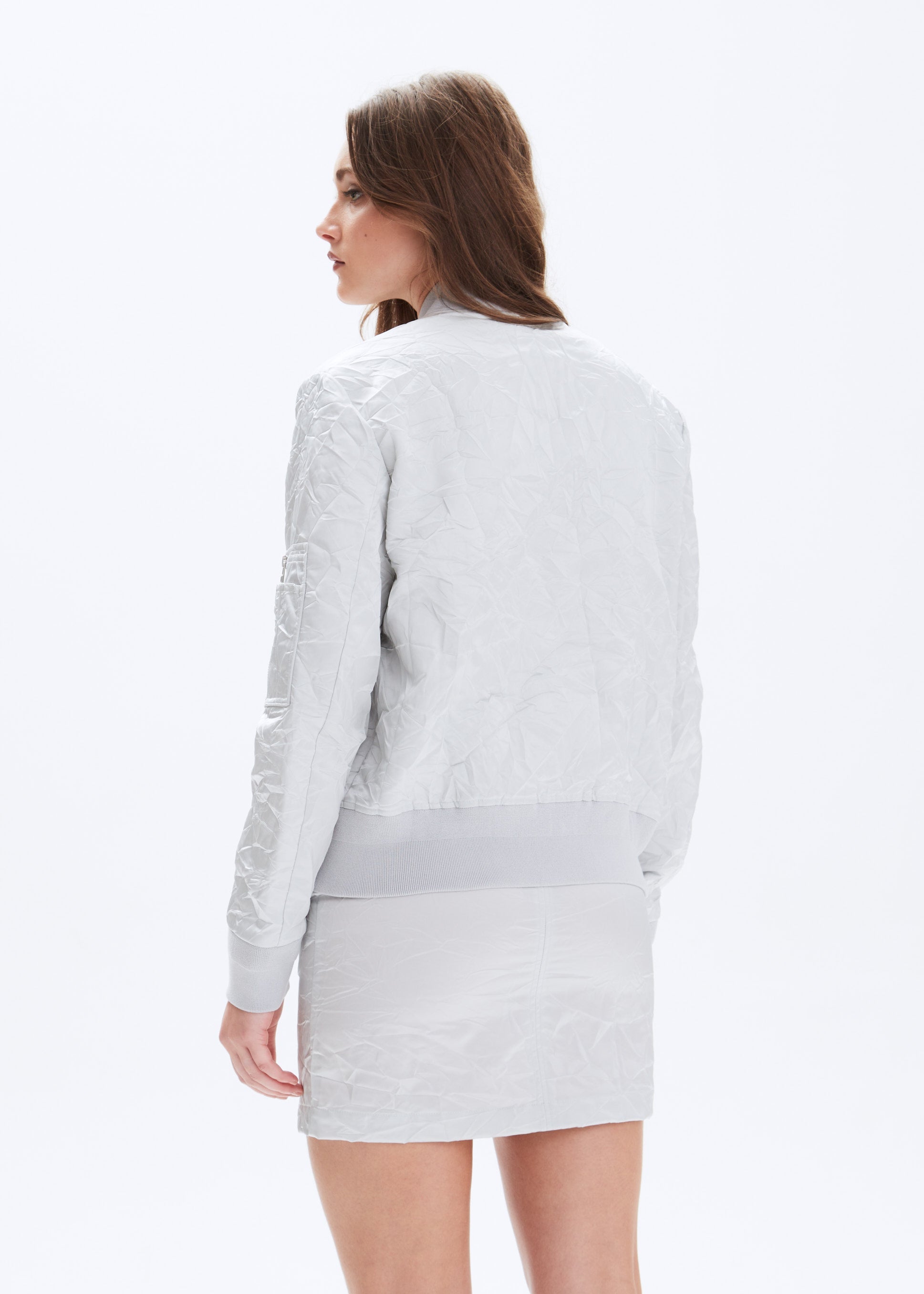 Woman wearing a light gray jacket and skirt set on a white background