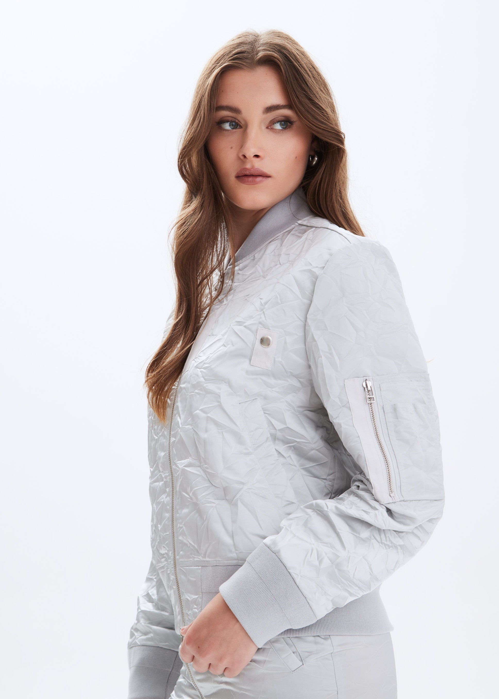 Woman wearing a light gray quilted jacket on a white background