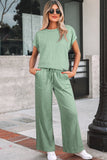 Woman wearing a green outfit standing on a sidewalk.