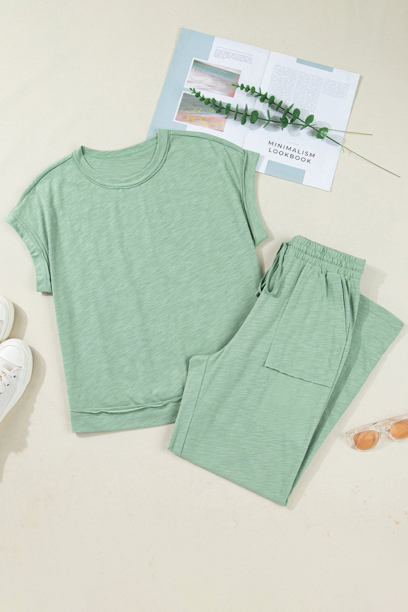 Green pajama set with a book and plant on a light background