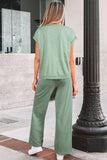 Person wearing a green outfit standing outdoors next to a building.