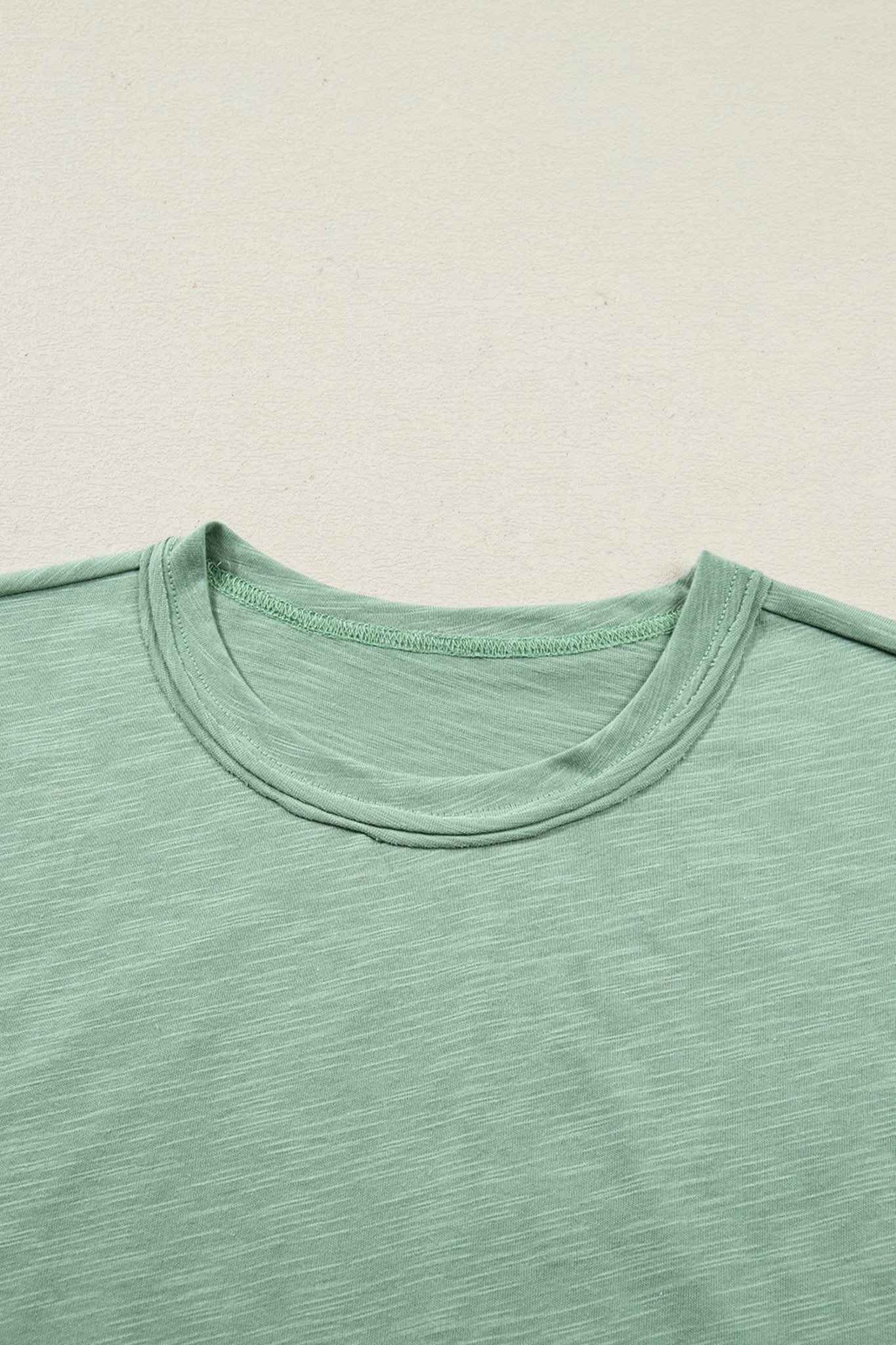 Close-up of a green t-shirt with a plain background