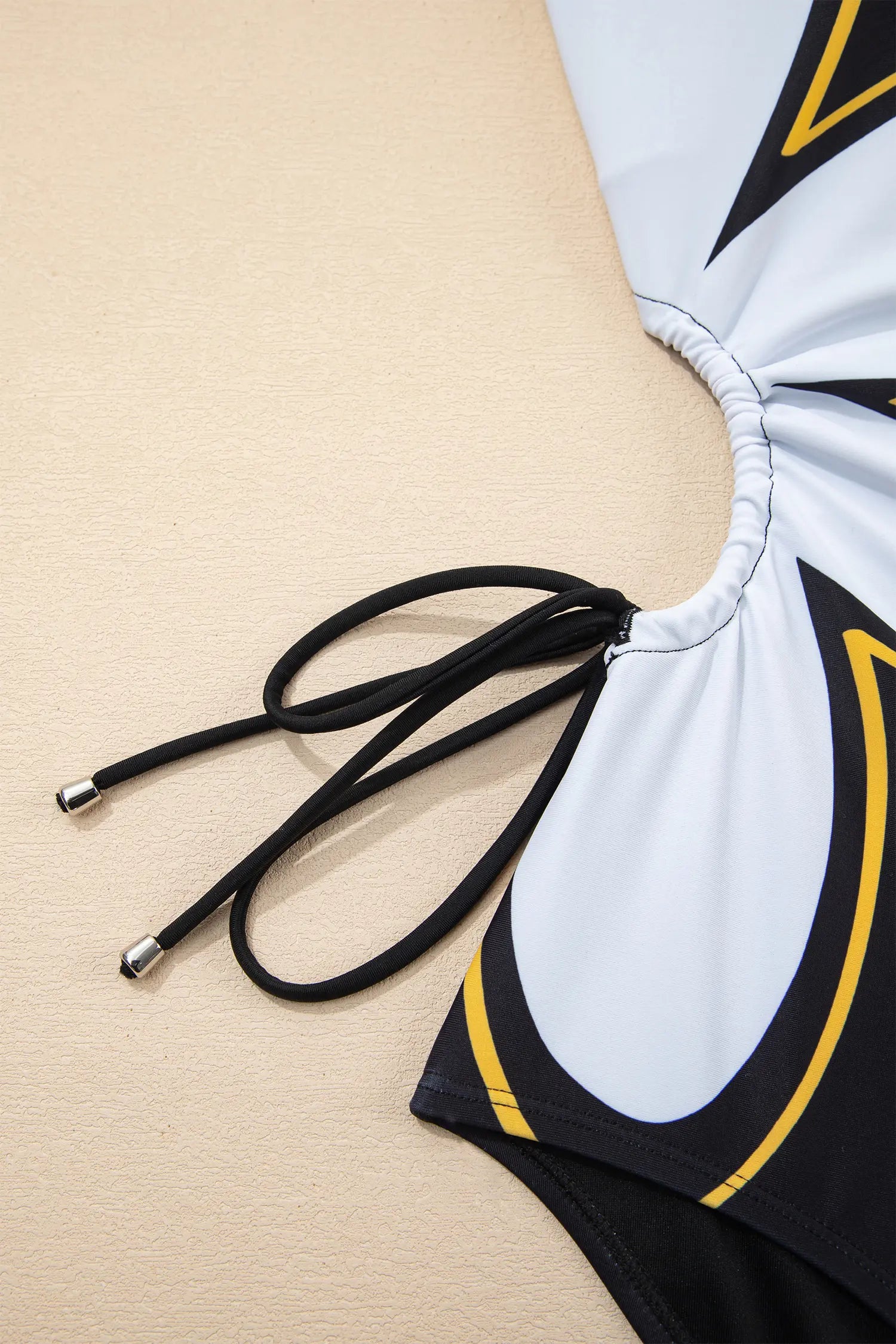Black and white swimsuit with yellow accents on a beige background