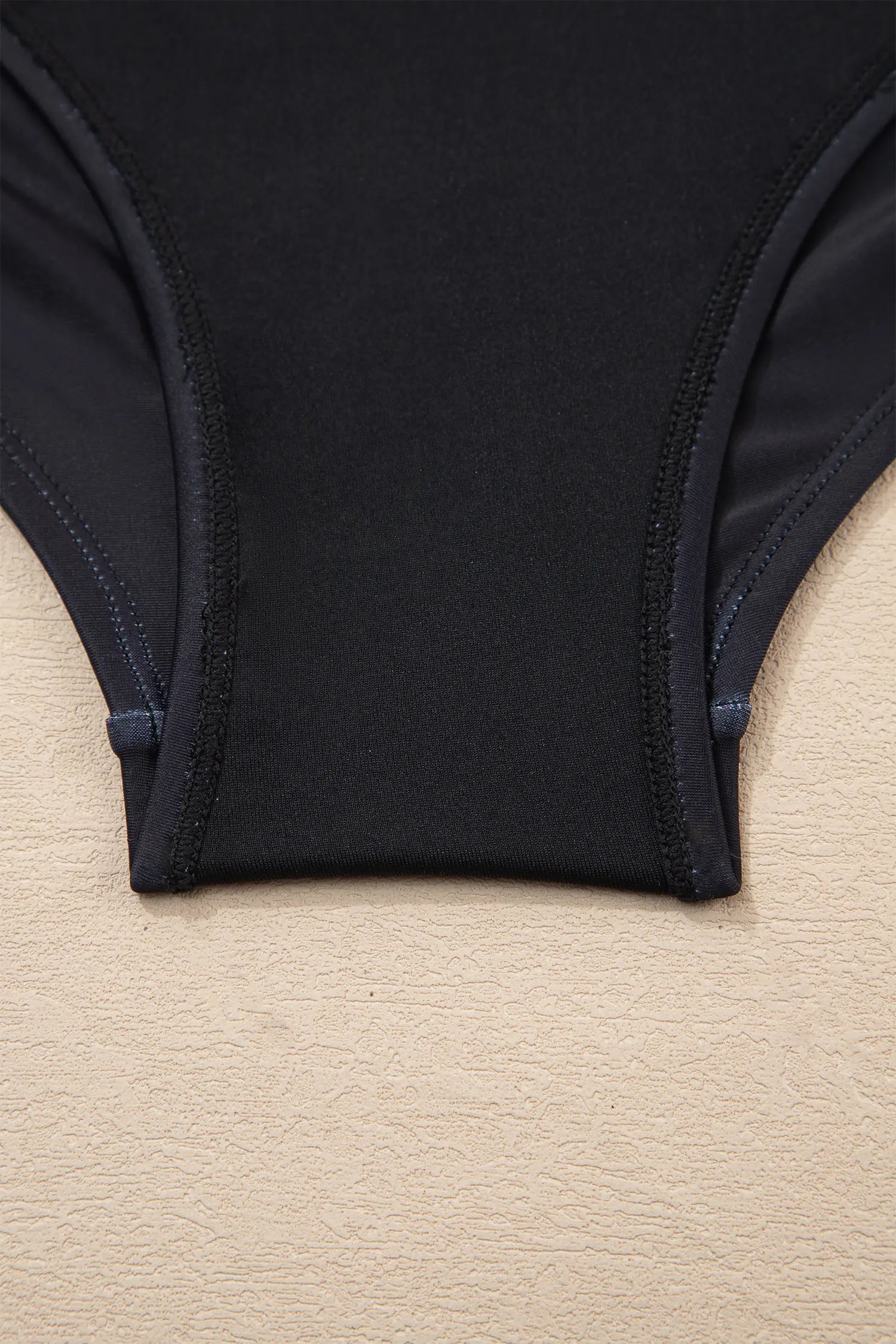 Black swimsuit on a beige surface