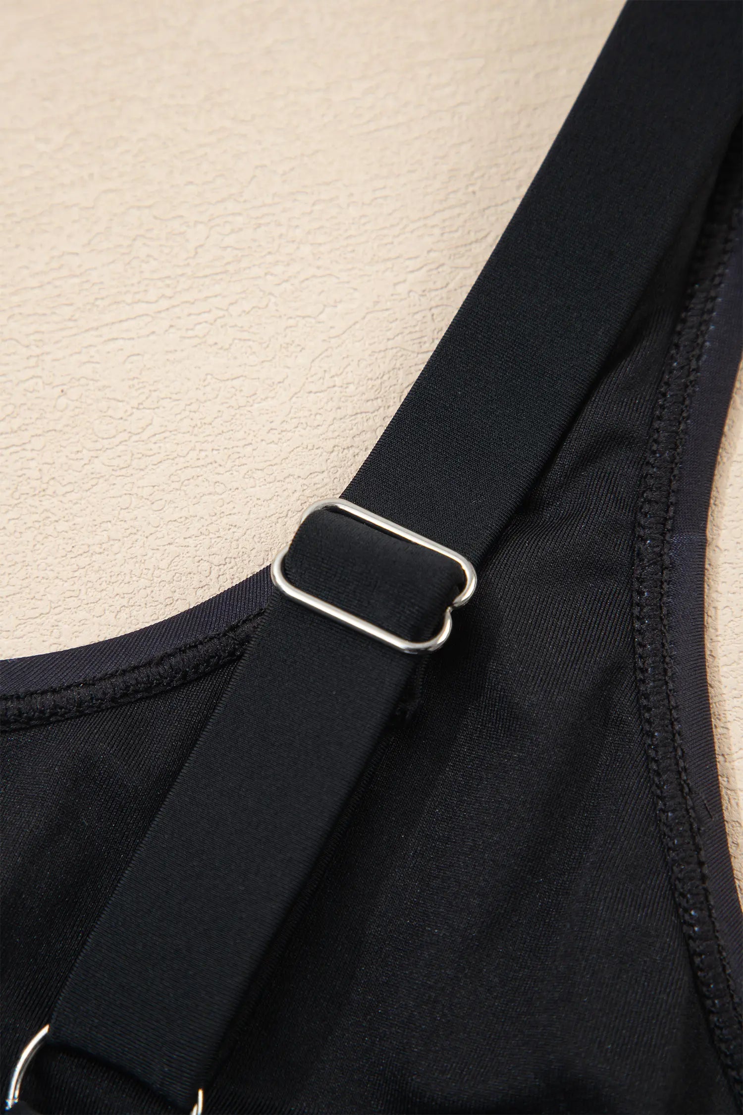 Close-up of a black strapless garment with a metal buckle on a beige background