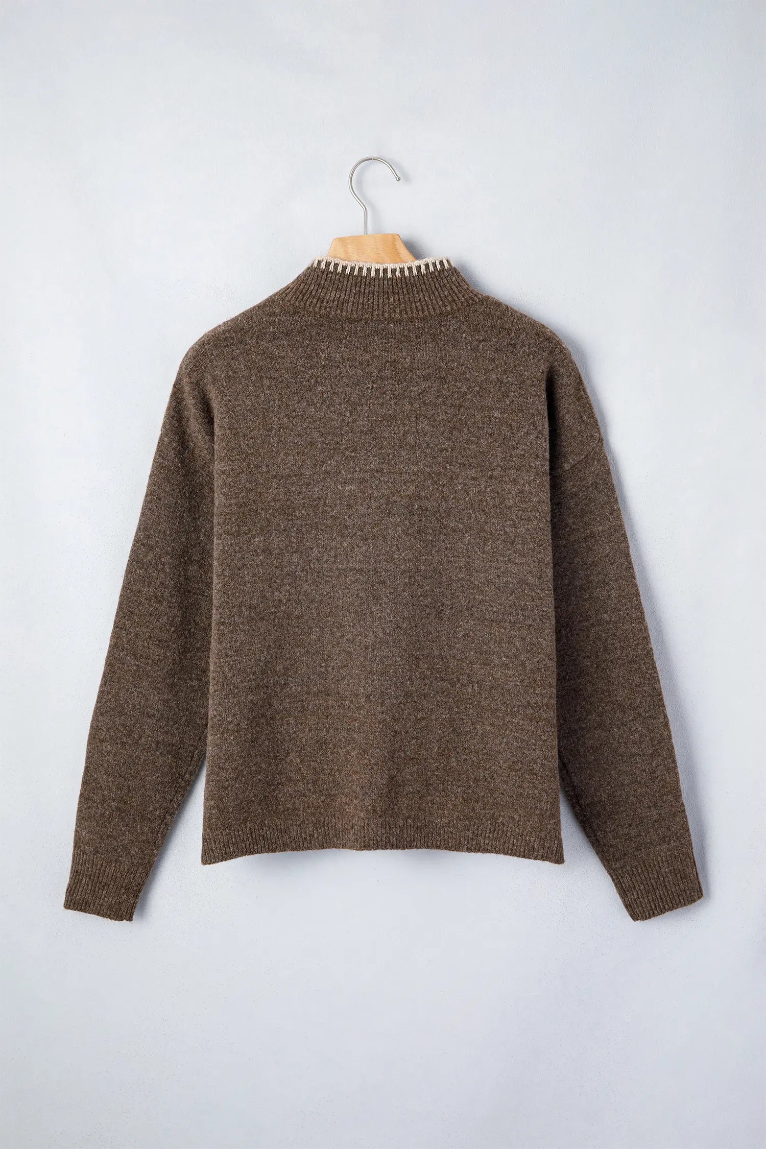 A brown knit sweater with a textured, heathered finish, hanging on a wooden hanger against a light gray background.