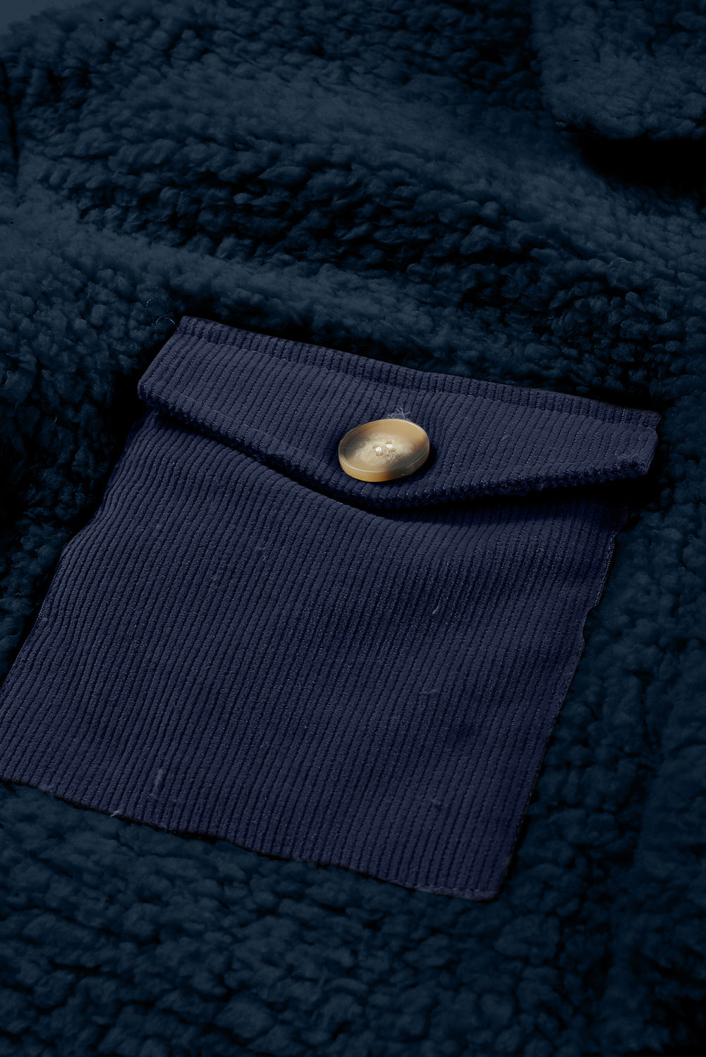 Close-up of a navy blue fabric with a button on a textured dark blue background.