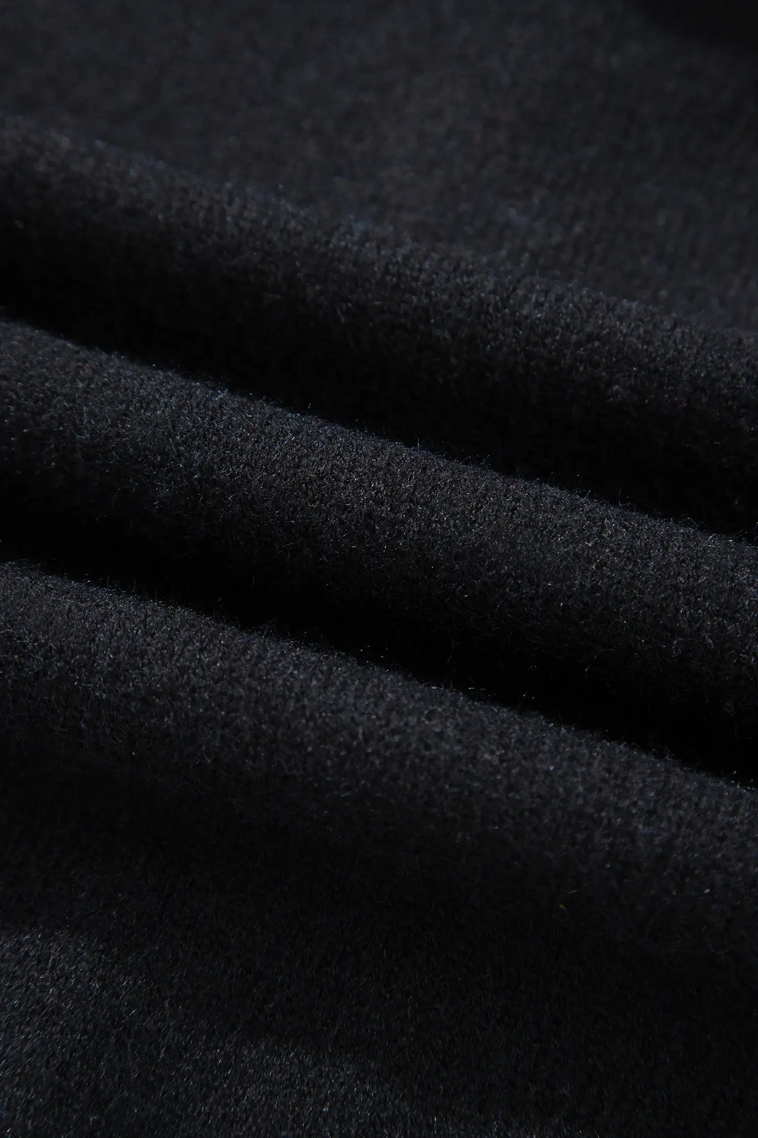 A close-up of dark charcoal gray textured fabric with soft diagonal folds.
