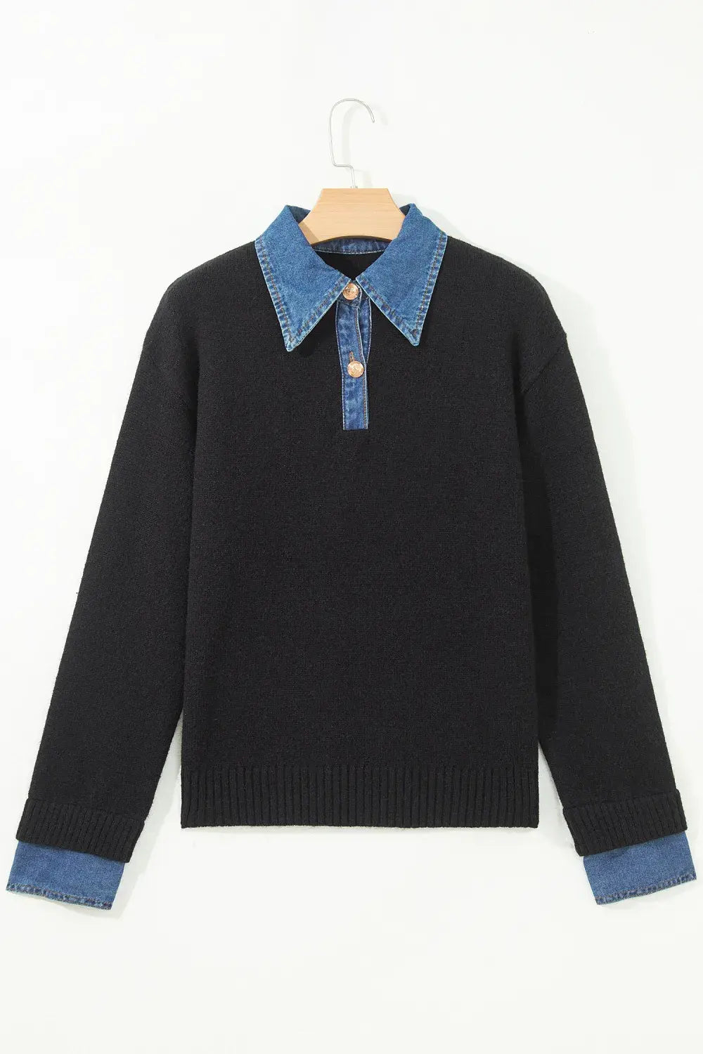 A black knit long-sleeve sweater with a blue denim collar and matching blue denim turned-back cuffs, hanging on a wooden hanger against a plain white background.
