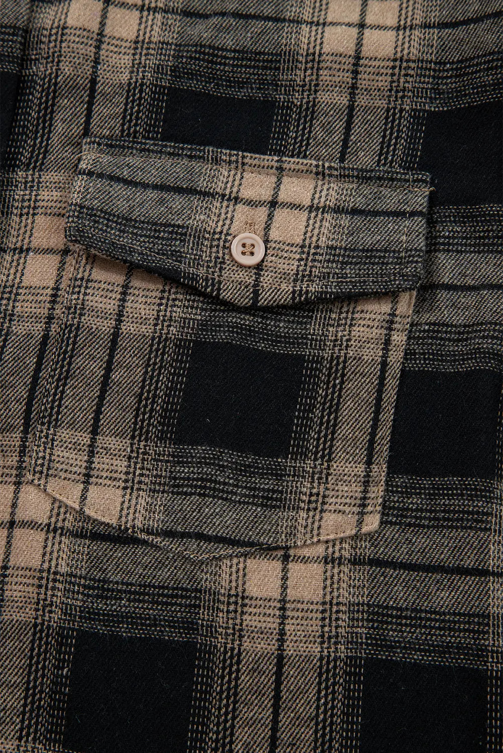 Close-up of a plaid shirt with a button on a pocket
