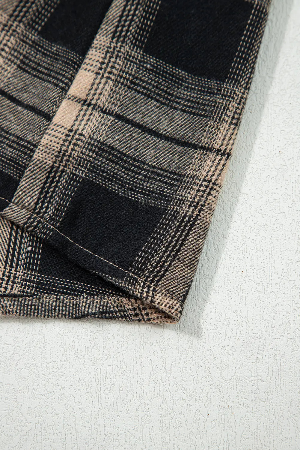 Close-up of a plaid fabric with black and beige pattern on a white background