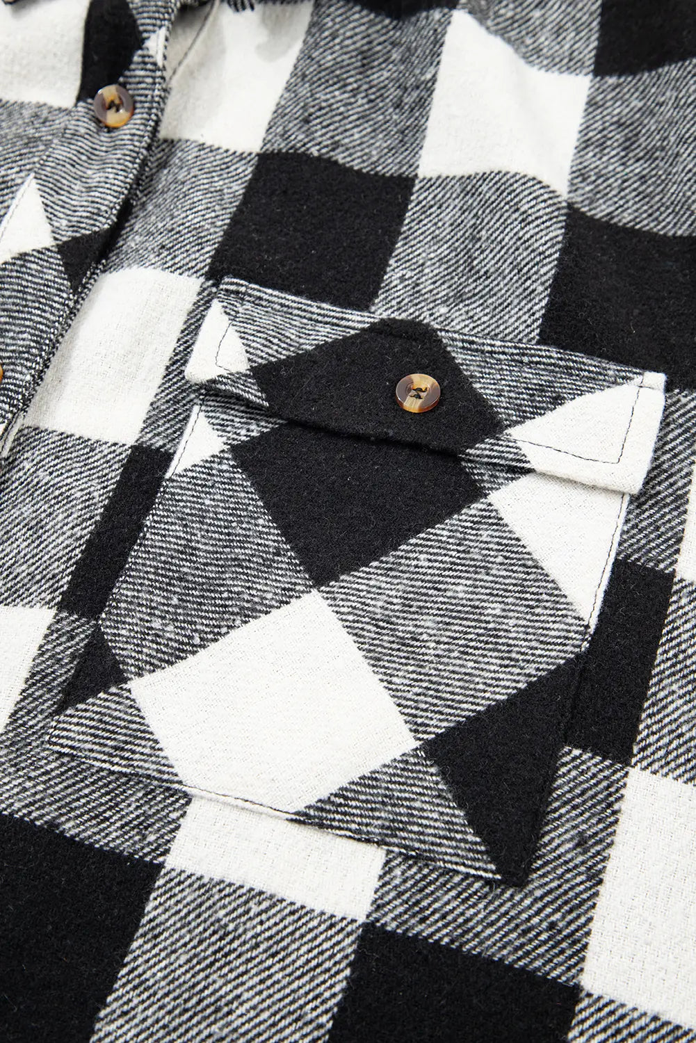 Close-up of a black and white checkered shirt with a button detail.