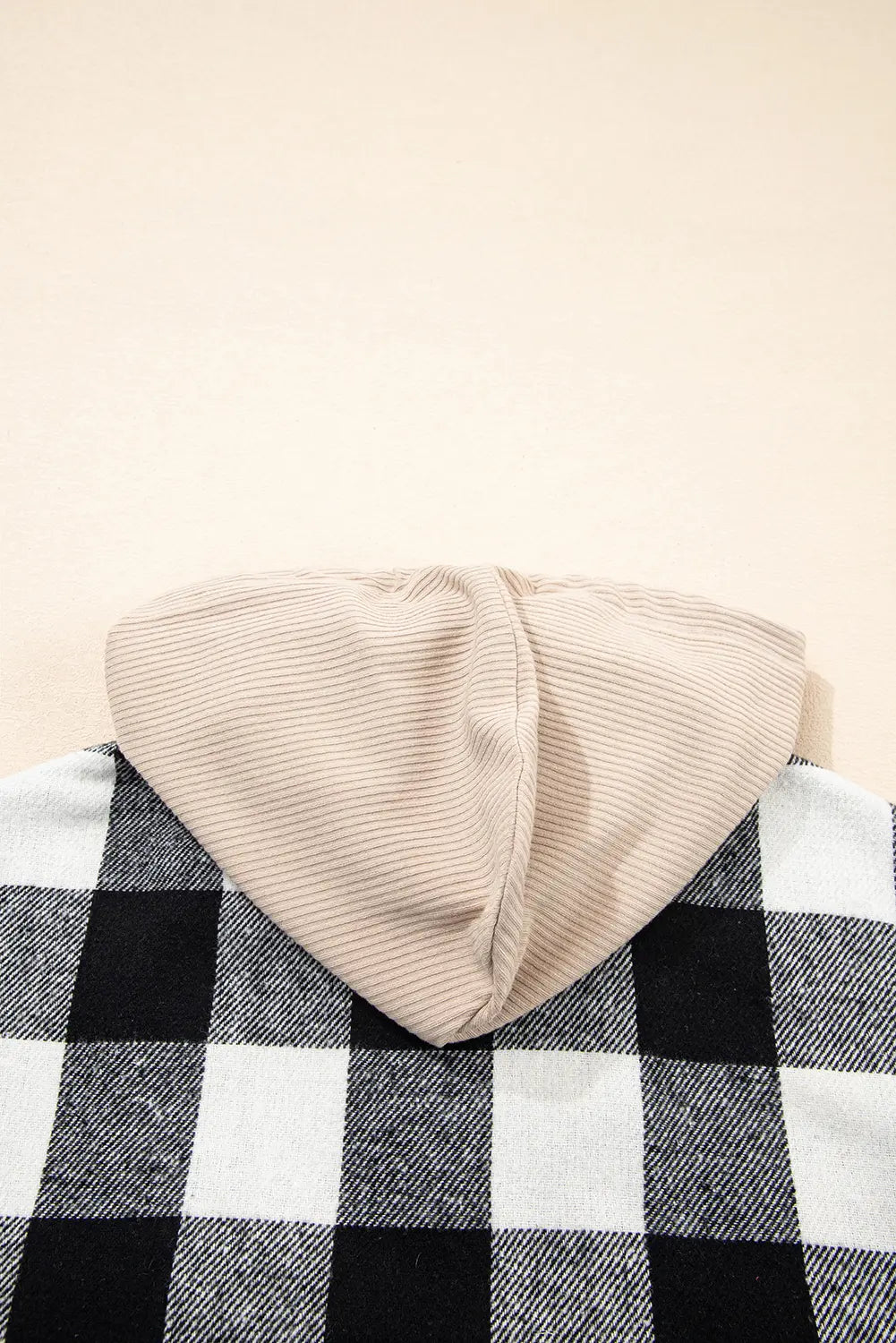 Beige knit beanie on a black and white checkered fabric background