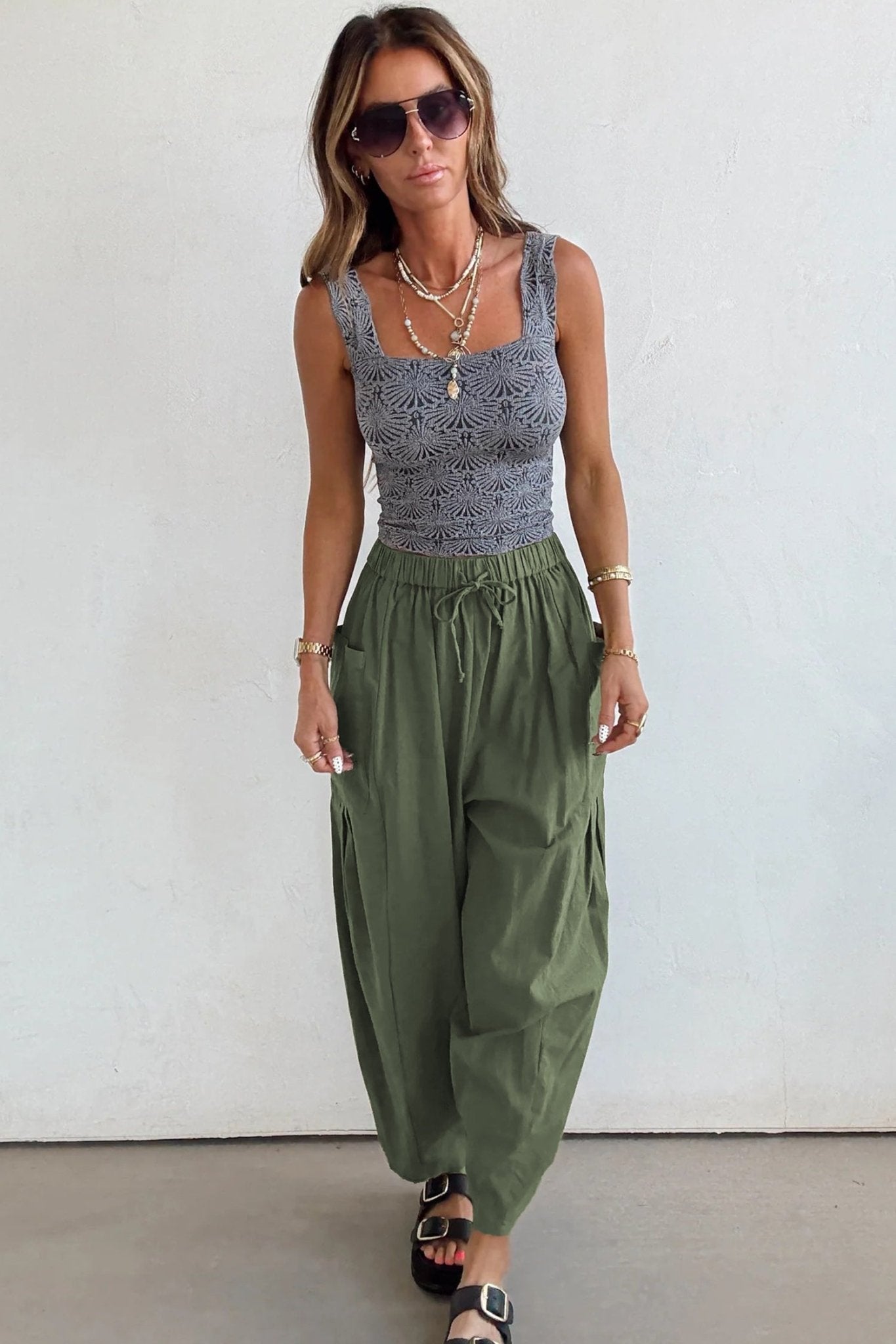 Woman wearing a sleeveless top and wide-leg pants against a white background