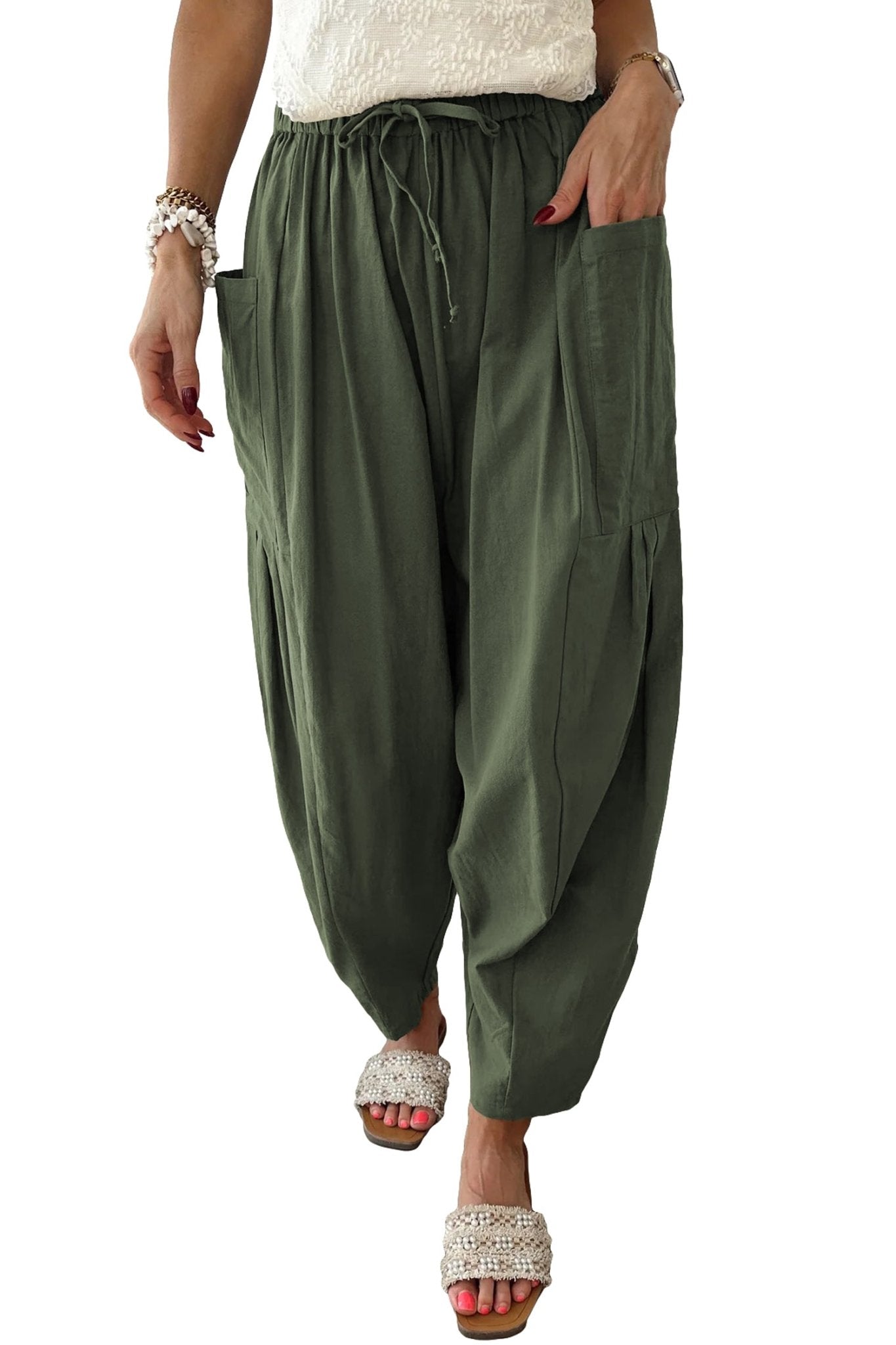 Person wearing olive green harem pants on a white background