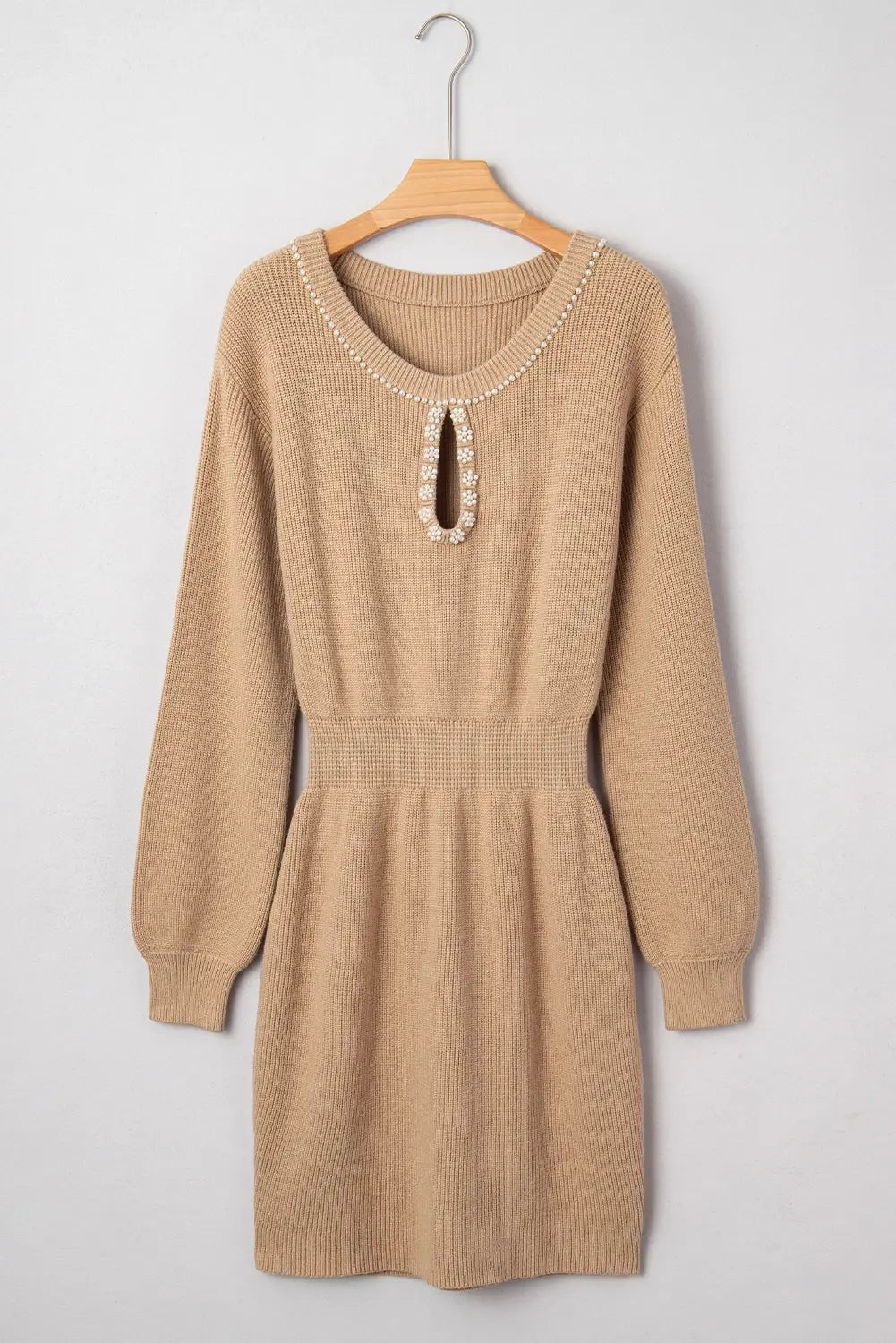 Beige sweater dress on a hanger against a light gray background