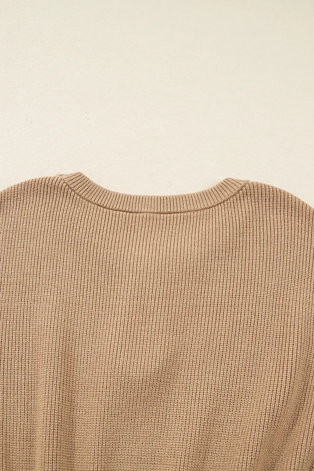 Close-up of a beige textured sweater on a beige background