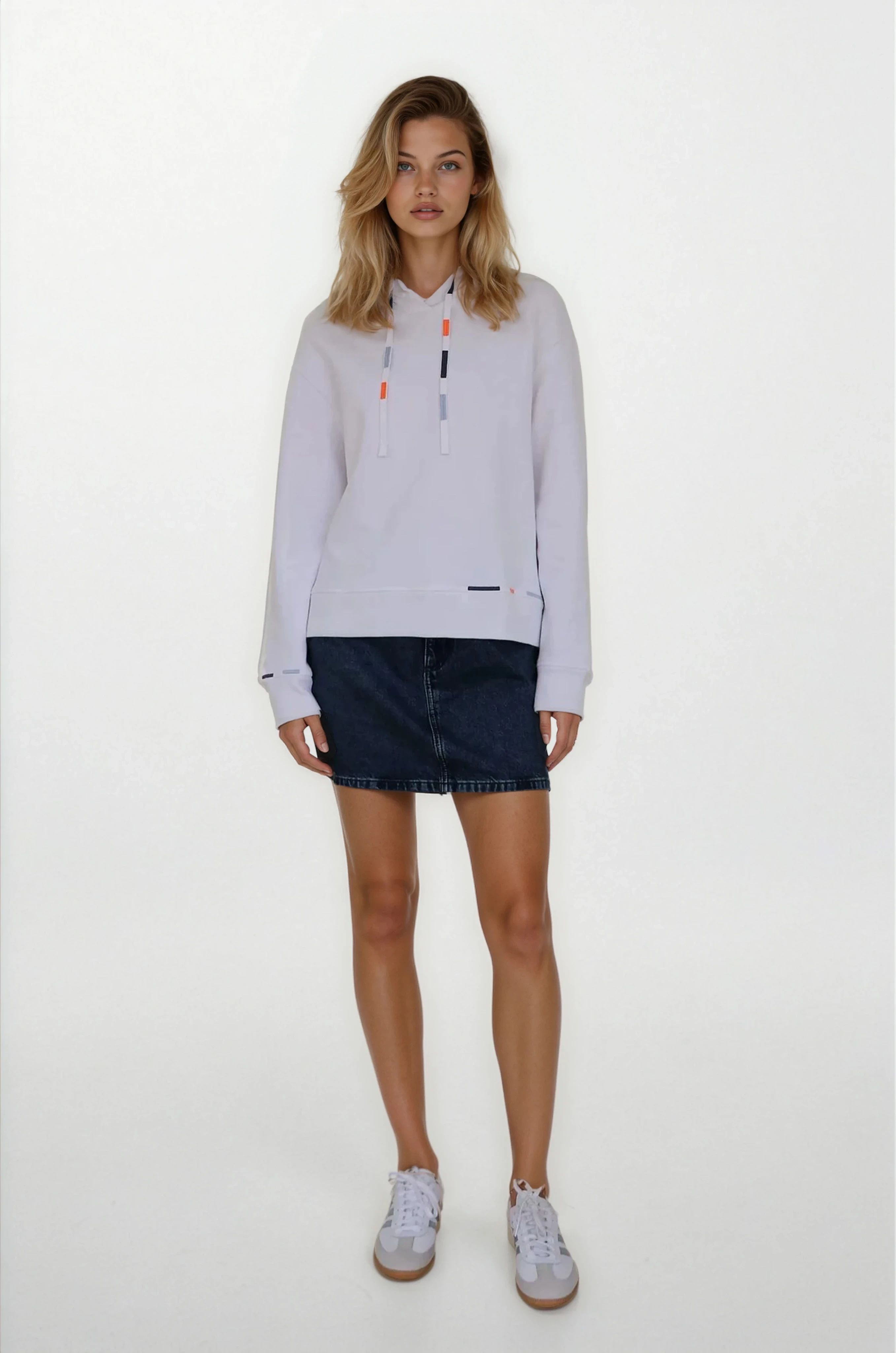 Woman wearing a light gray long-sleeve shirt with a collar and dark denim shorts on a white background