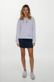 Woman wearing a light gray long-sleeve shirt with a collar and dark denim shorts on a white background