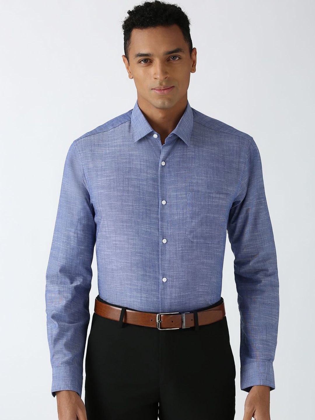 Man wearing a blue checkered shirt and black pants on a white background