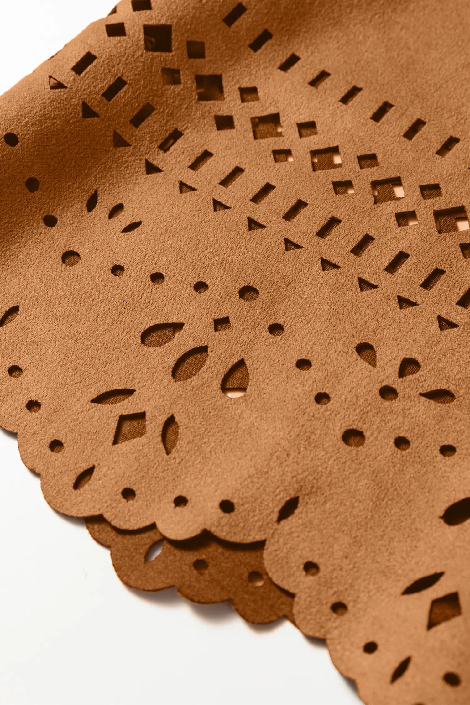 Close-up of brown leather with laser-cut patterns on a white background