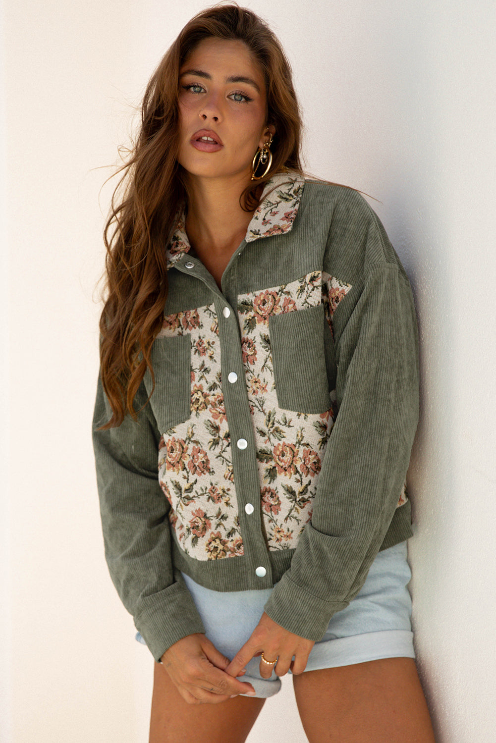 Woman wearing a green floral-patterned jacket against a white background