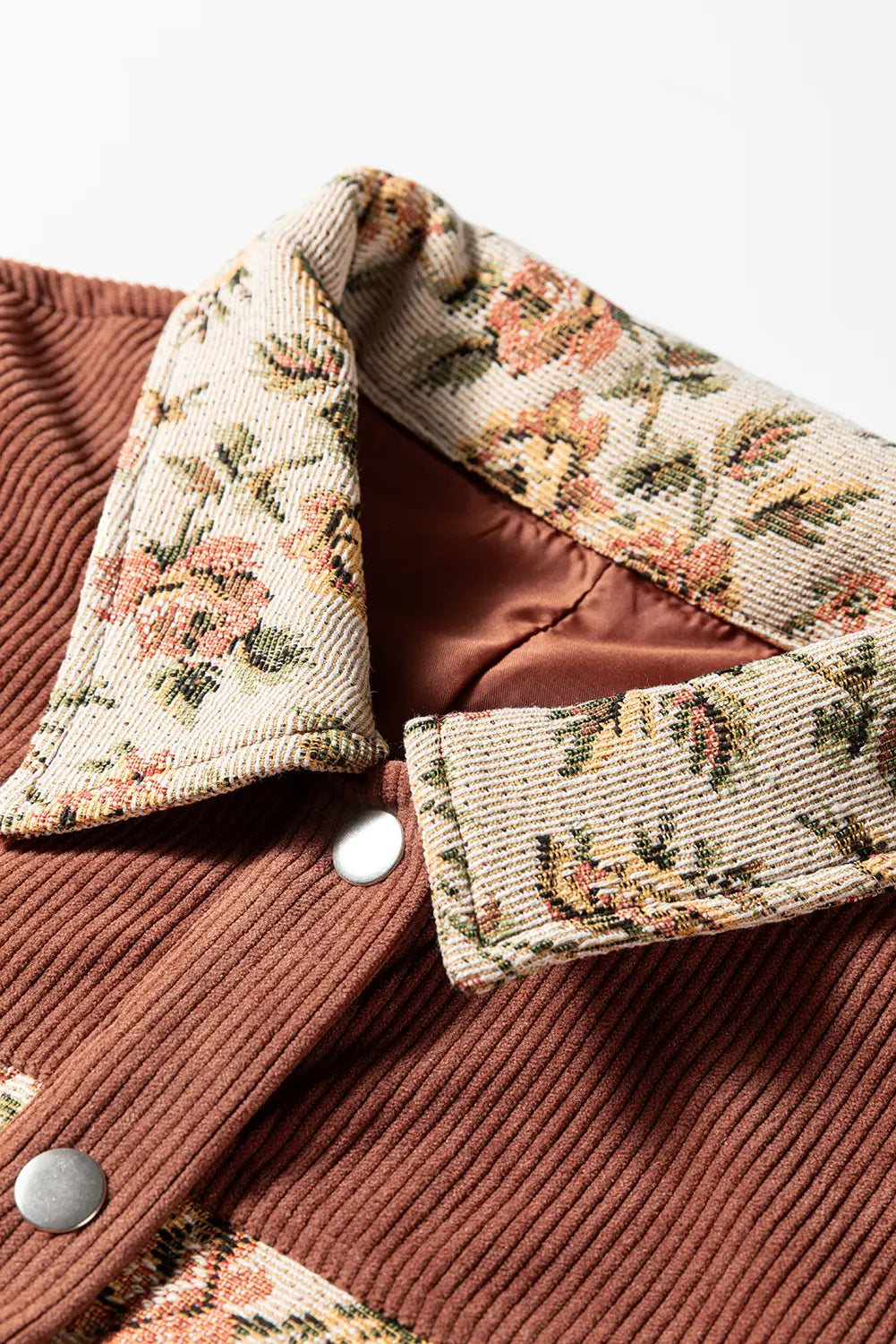 Close-up of a brown coat with floral patterned collar and buttons on a white background