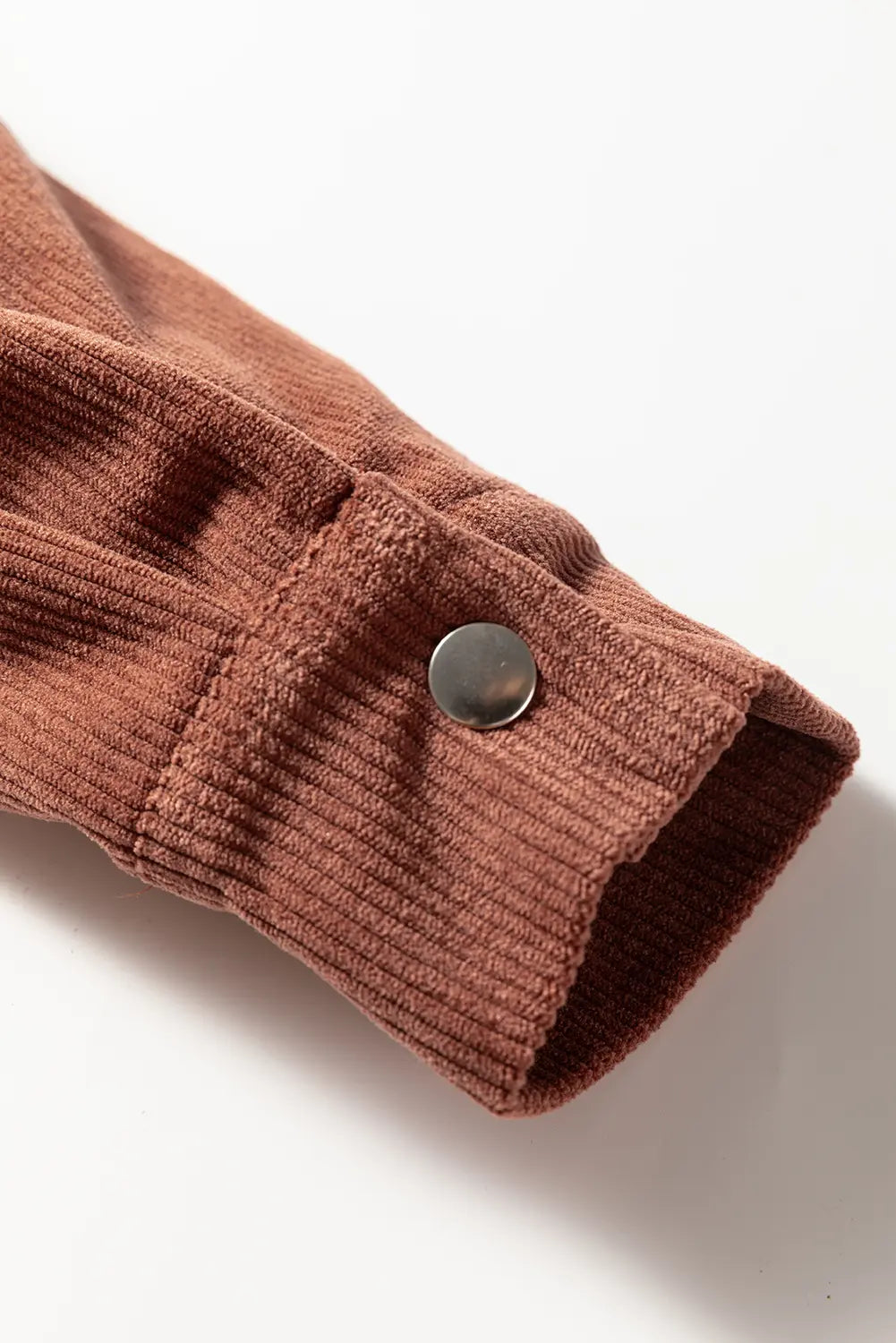 Brown textured fabric with a metal button on a white background