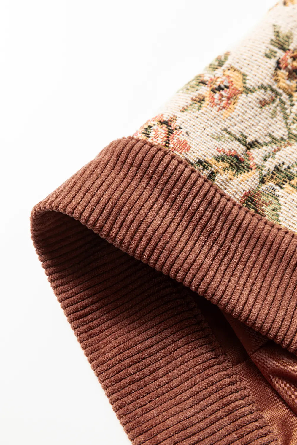 Close-up of a brown textured fabric with floral patterned trim on a white background