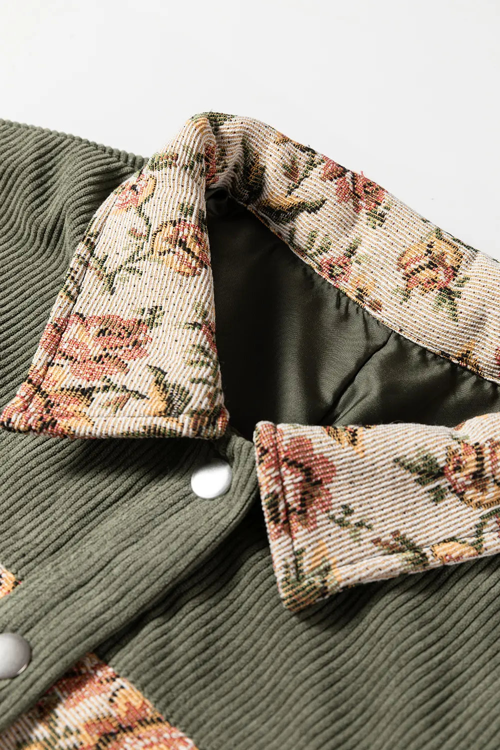 Close-up of a green coat with floral-patterned collar and cuffs on a light gray background