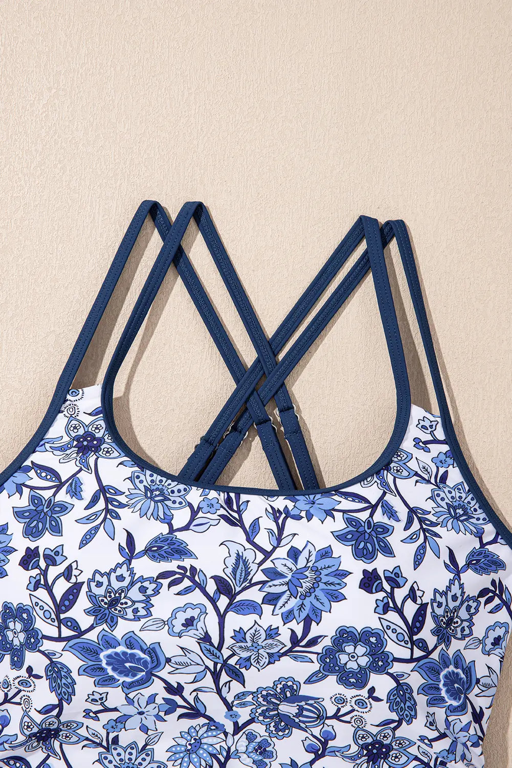 Blue floral-patterned top with thin straps on a beige background