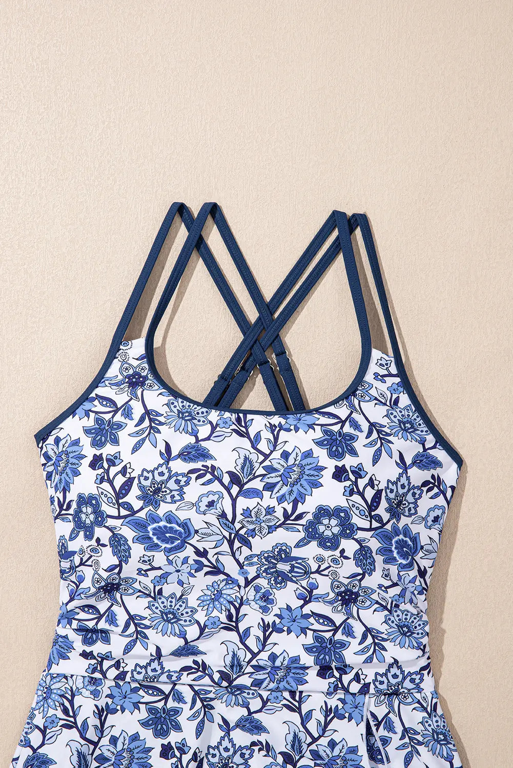 Blue floral dress with criss-cross straps on a beige background