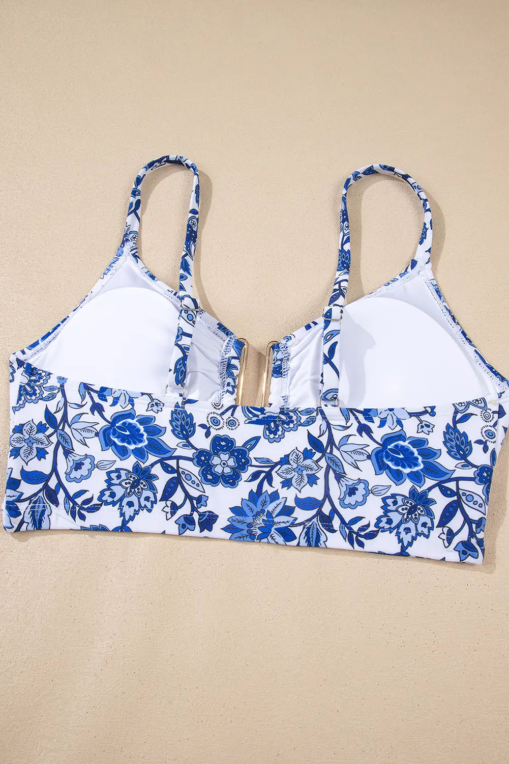 A women's underwire bra with a blue and white floral print on the cups and lower band, and solid white on the upper straps and inner cups, laid flat on a beige background.