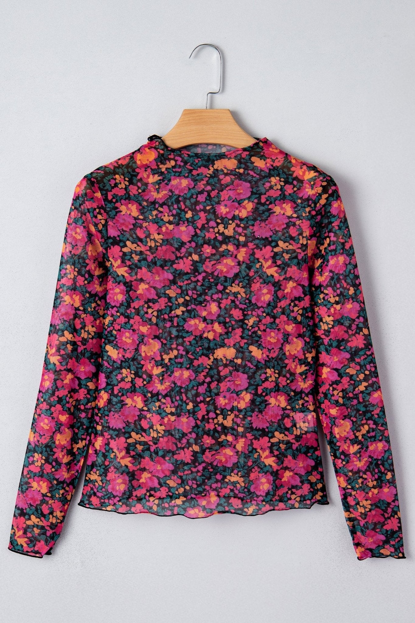 Floral patterned top on a hanger against a white background