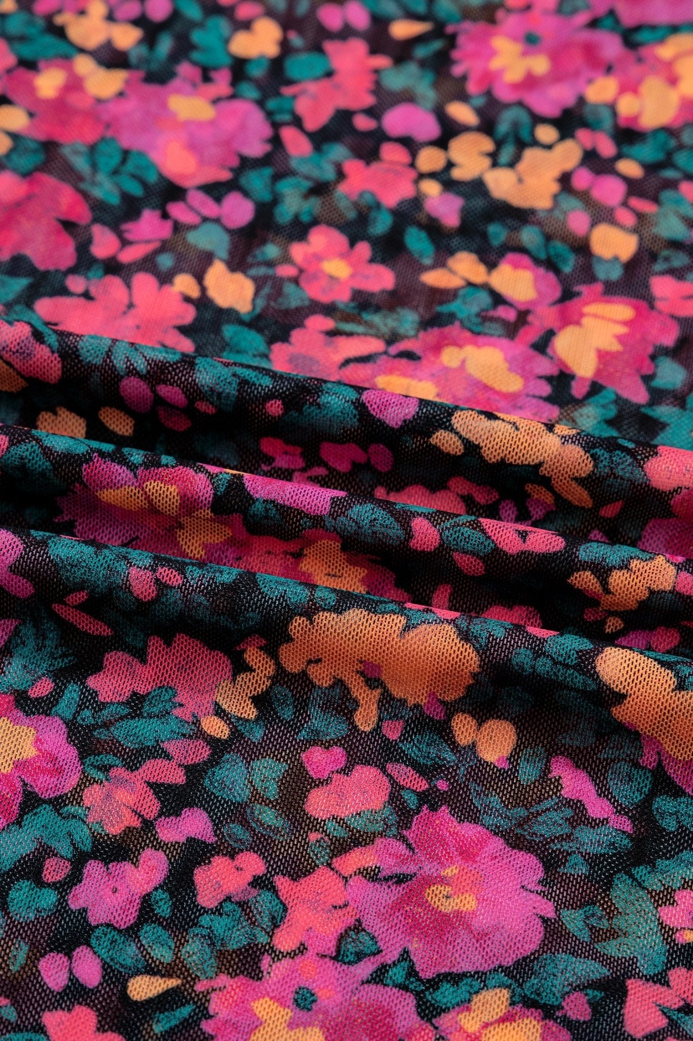 Close-up of colorful floral fabric with pink, orange, and green flowers on a black background.