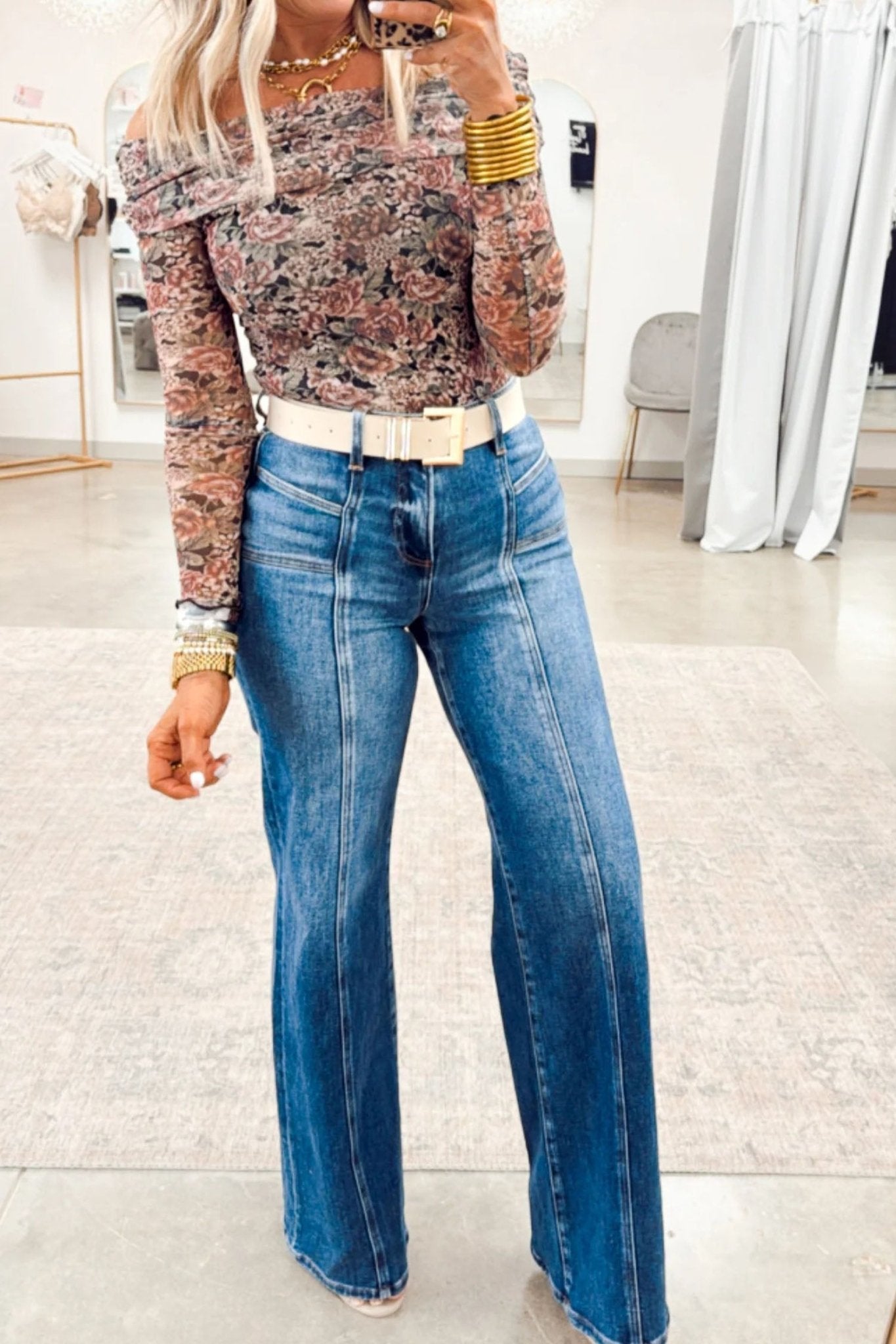 Person wearing a patterned top and blue jeans in an indoor setting