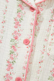 Close-up of white muslin shirt with pink-green floral print and pink piping.